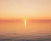 Warm Hawaiian sunrise over calm, still ocean water